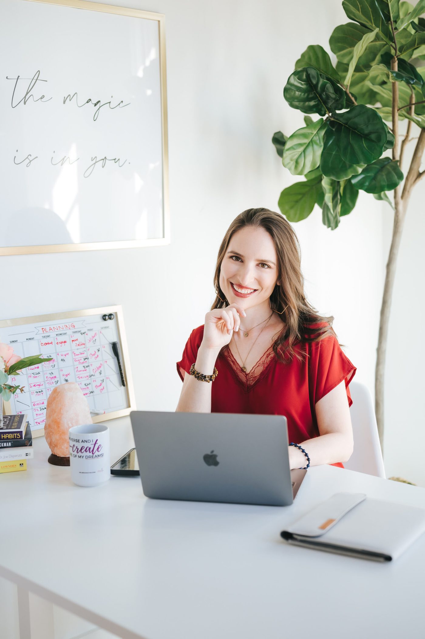 Meliss Jakubovic smiling at her desk beside her laptop and planning board